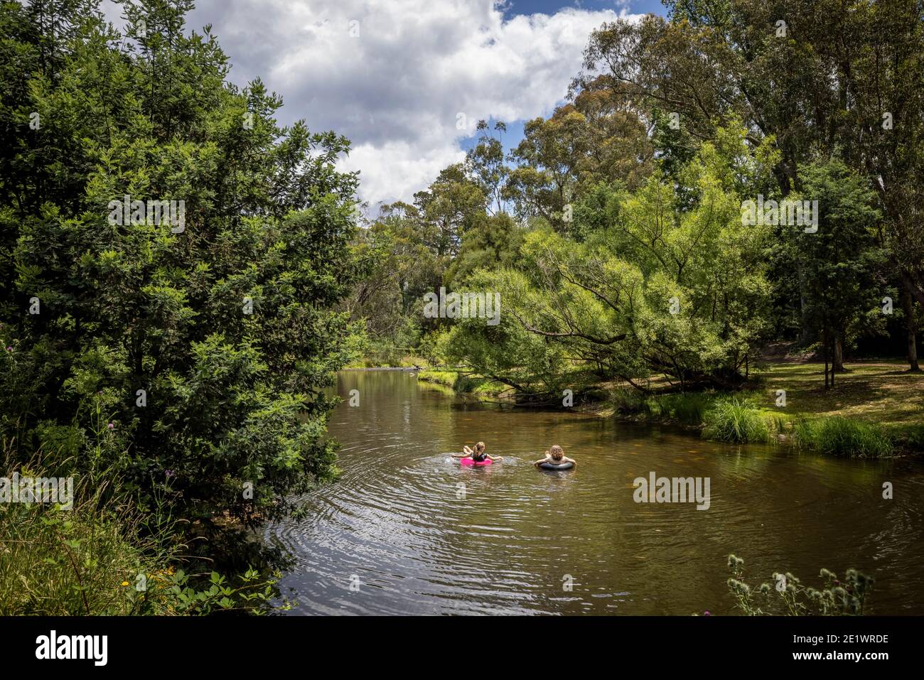 Two unidentifiable people floating down the river in Bright, Victoria, Australia Stock Photo