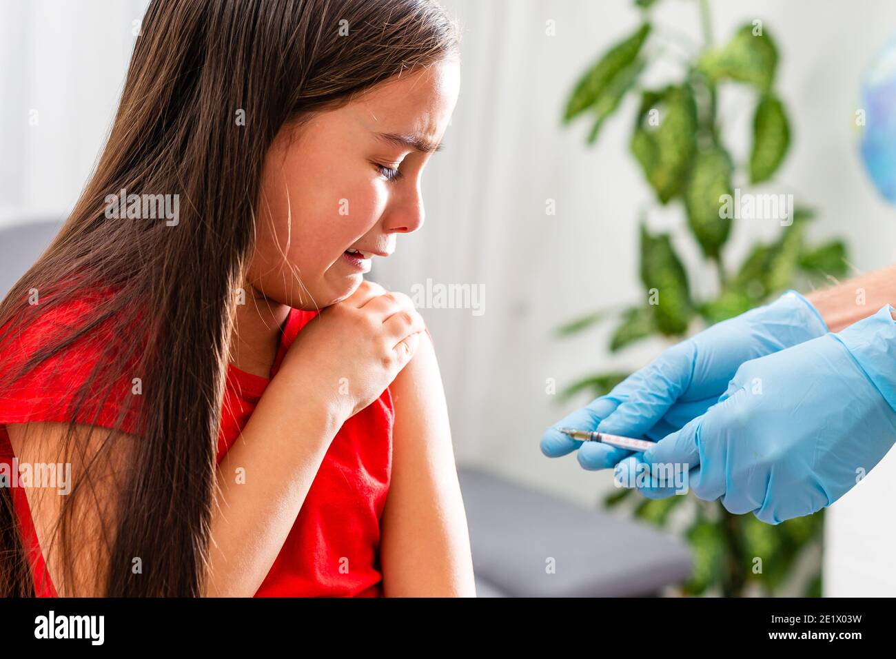 Doctor holds syringe to vaccinate sick baby with injection. Crying and fear a little patient before the injection. Stock Photo