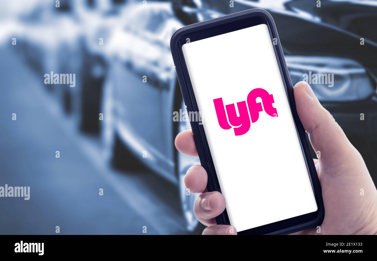 Galicia, Spain; january 09 2021: Hand holding a smart phone with Lyft logo on screen and blurry cars on background Stock Photo