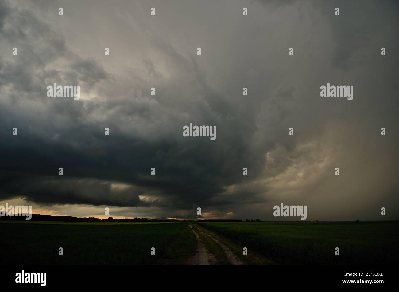 dark storm clouds with rain over a field with road Stock Photo - Alamy