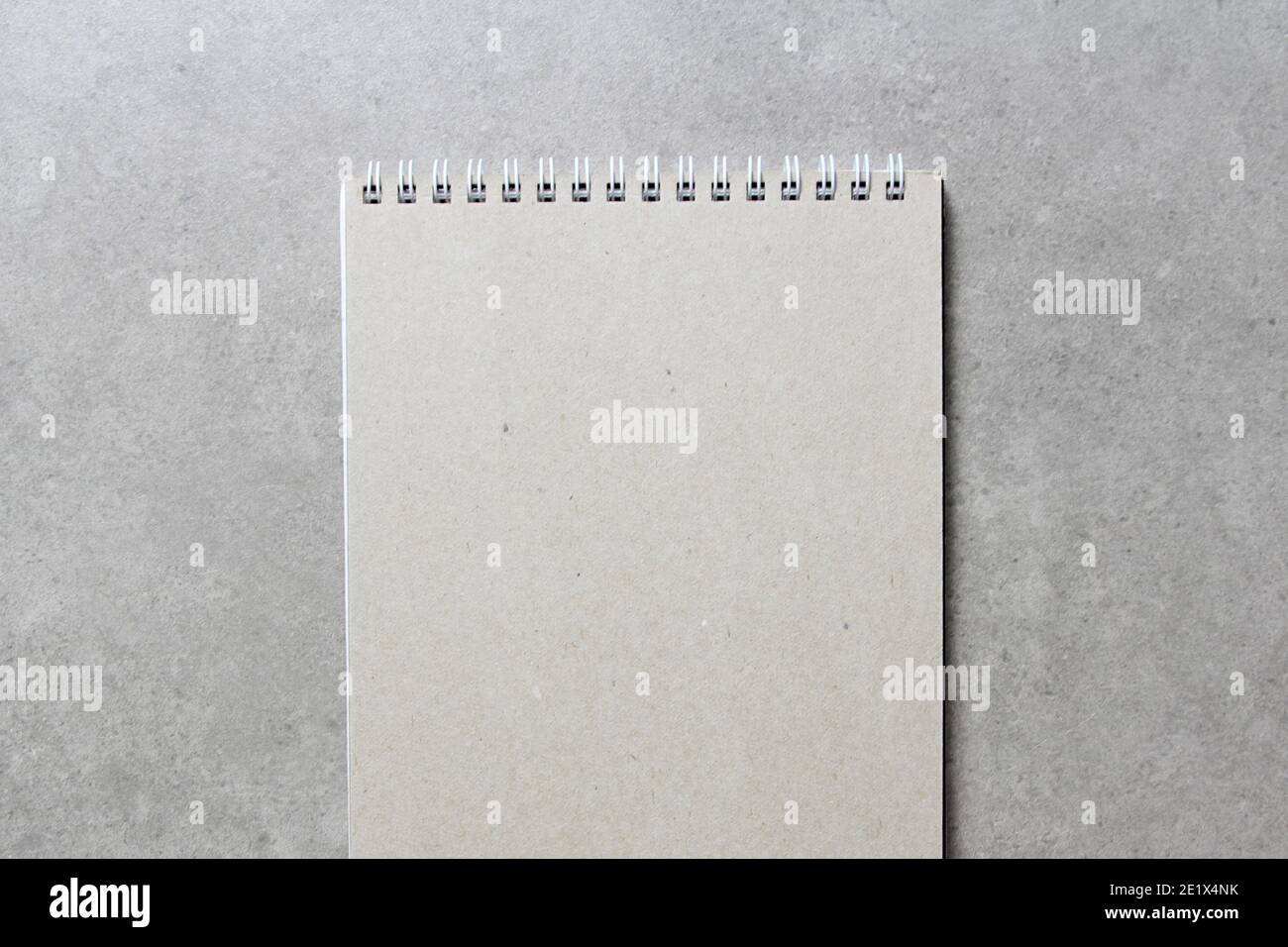 A spring notebook with a sheet of craft paper A5 on light grey concrete background. Concept of new idea, business plan and strategy, development and i Stock Photo