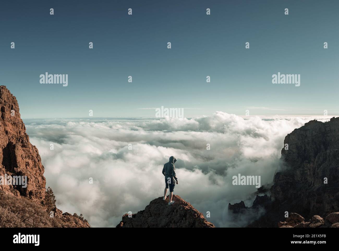 Man standing on the mountain peak above the clouds Stock Photo