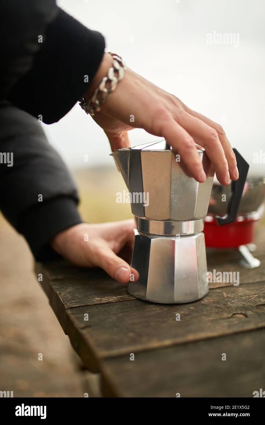Traveler man making camping coffee outdoor with metal geyser coffee maker  on a gas burner, step by step. Travel activity for relaxing, bushcraft,  adve Stock Photo - Alamy