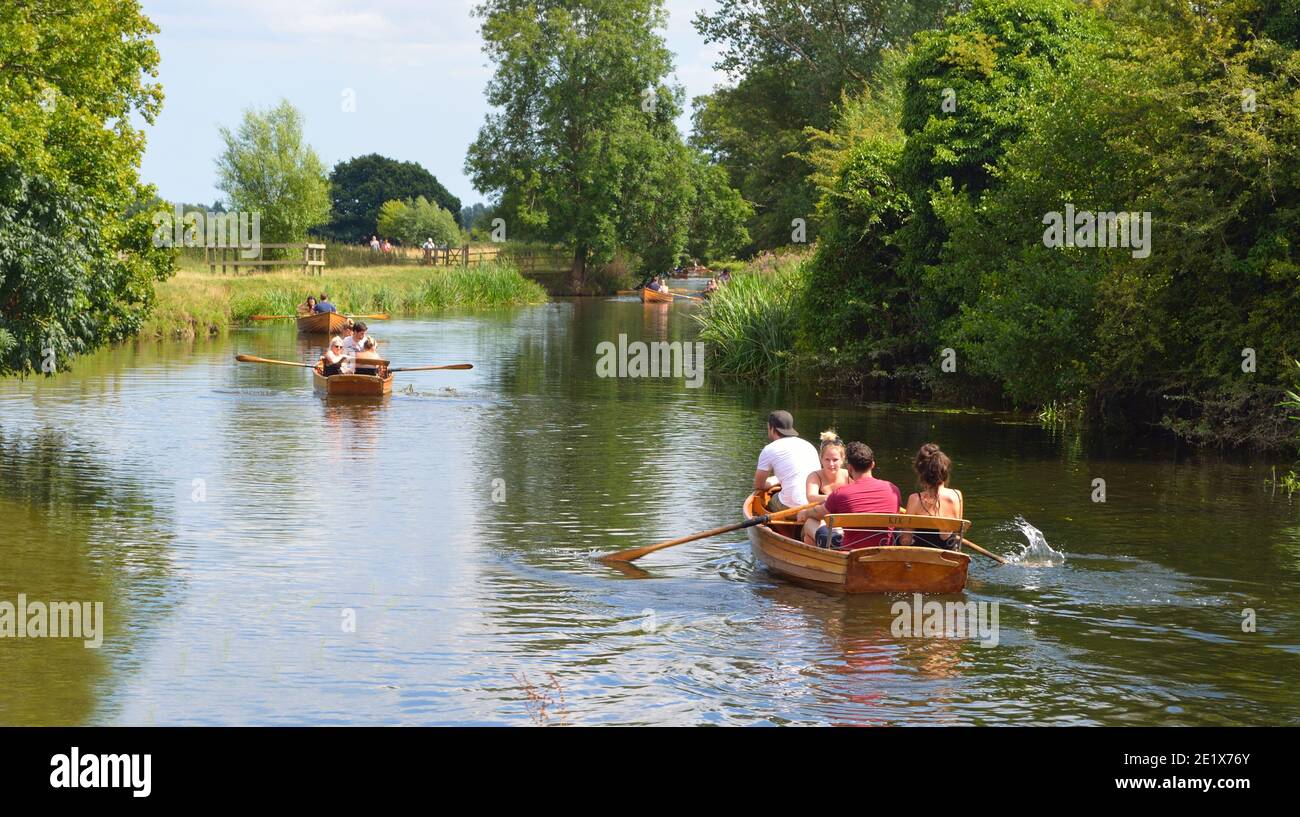People rowing boats on the river Stour on the Essex - Suffolk border enjoying the summer sunshine. Stock Photo