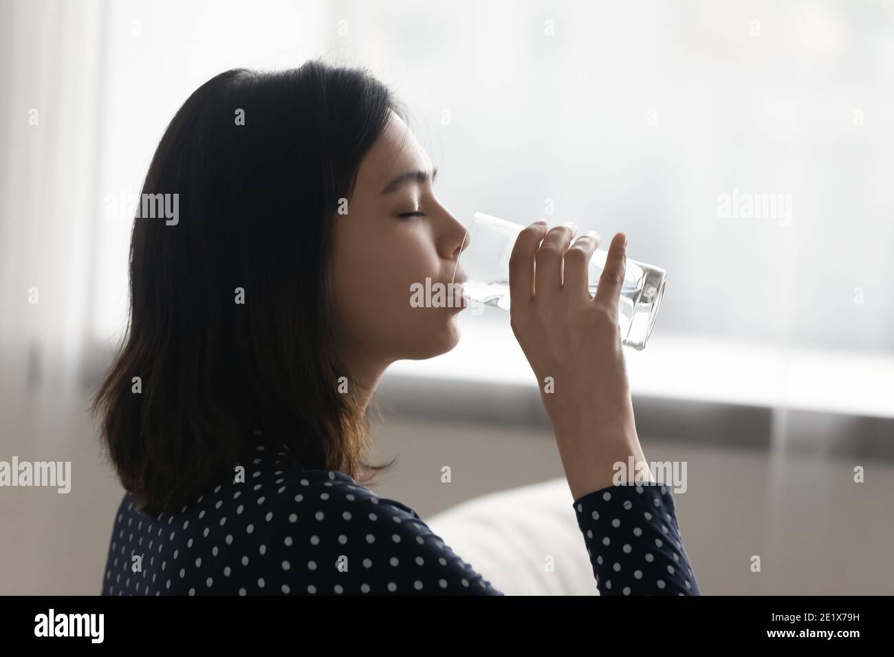 Young multiracial asian korean woman drinking cool distilled water. Stock Photo