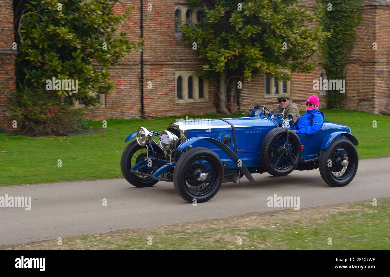 Vintage blue racing car being driven past  front of old building. Stock Photo