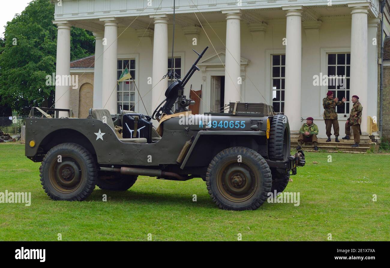 World War 2 Jeep mounted Machine gun men in ww2 military uniforms with red berets in front of old building. Stock Photo