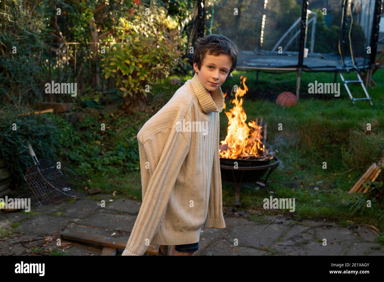 Edinburgh, Scotland, UK. November 2020. A young boy wearing his Dad’s old jumper and playing in the back garden Stock Photo