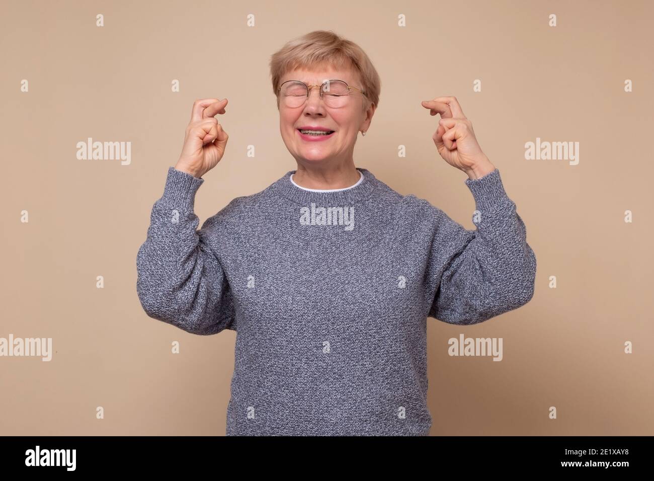 Senior caucasian woman gesturing finger crossed smiling with hope and eyes closed. Luck and superstitious concept. Stock Photo