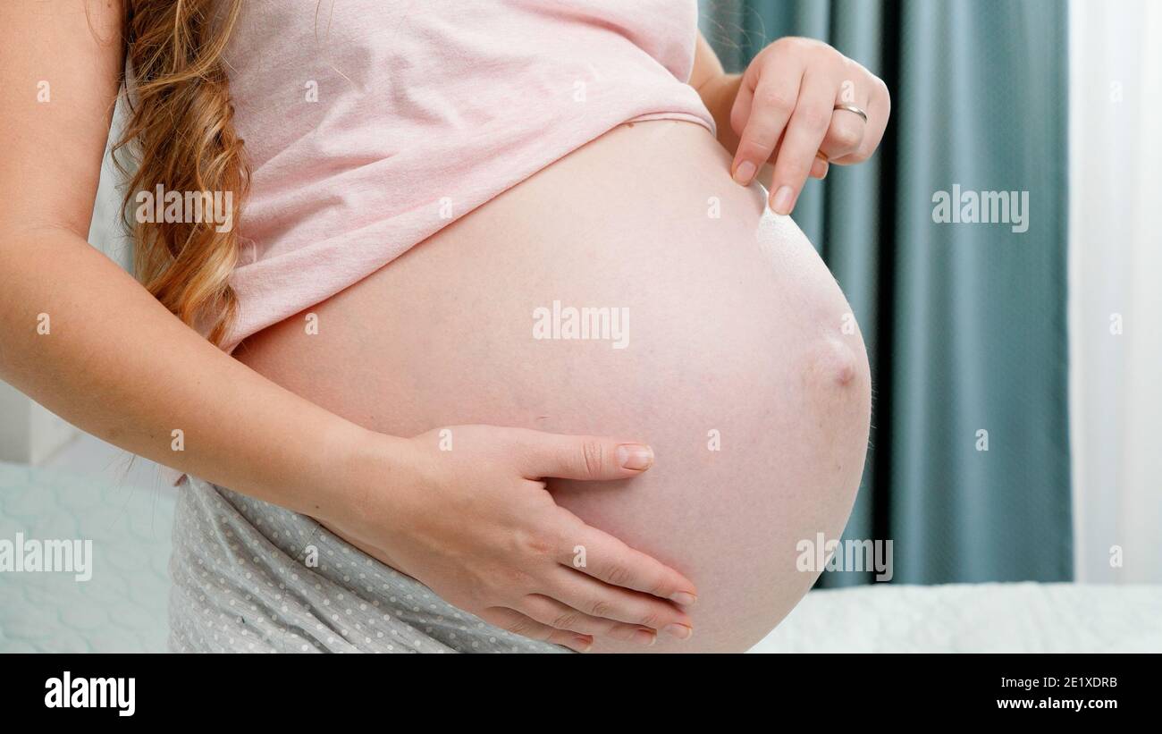 Closeup of pregnant woman walking with fingers acroos her bog belly