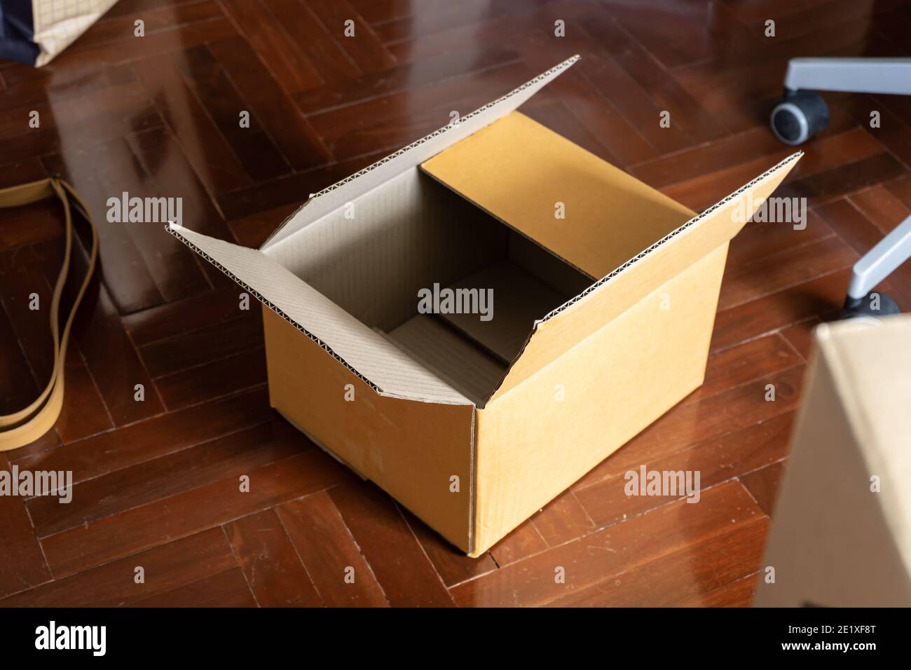 Empty cardboard box on wooden floor. Preparing to relocation. Stock Photo