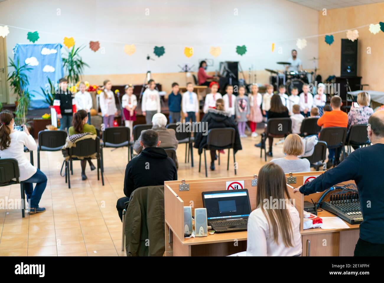 Parents at the performance of children in kindergarten or school. Children on stage. Many parents are watching the kids performance in the hall during Stock Photo