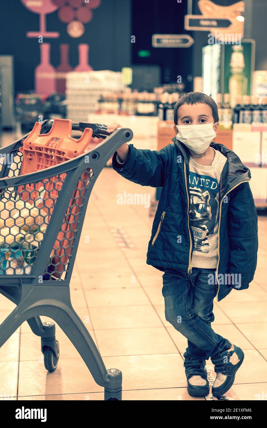 Boy wears protected mask in store. Shopping time during coronavirus outbreak. Boy in a medical mask. Shopping with kids during virus outbreak. Boy in Stock Photo