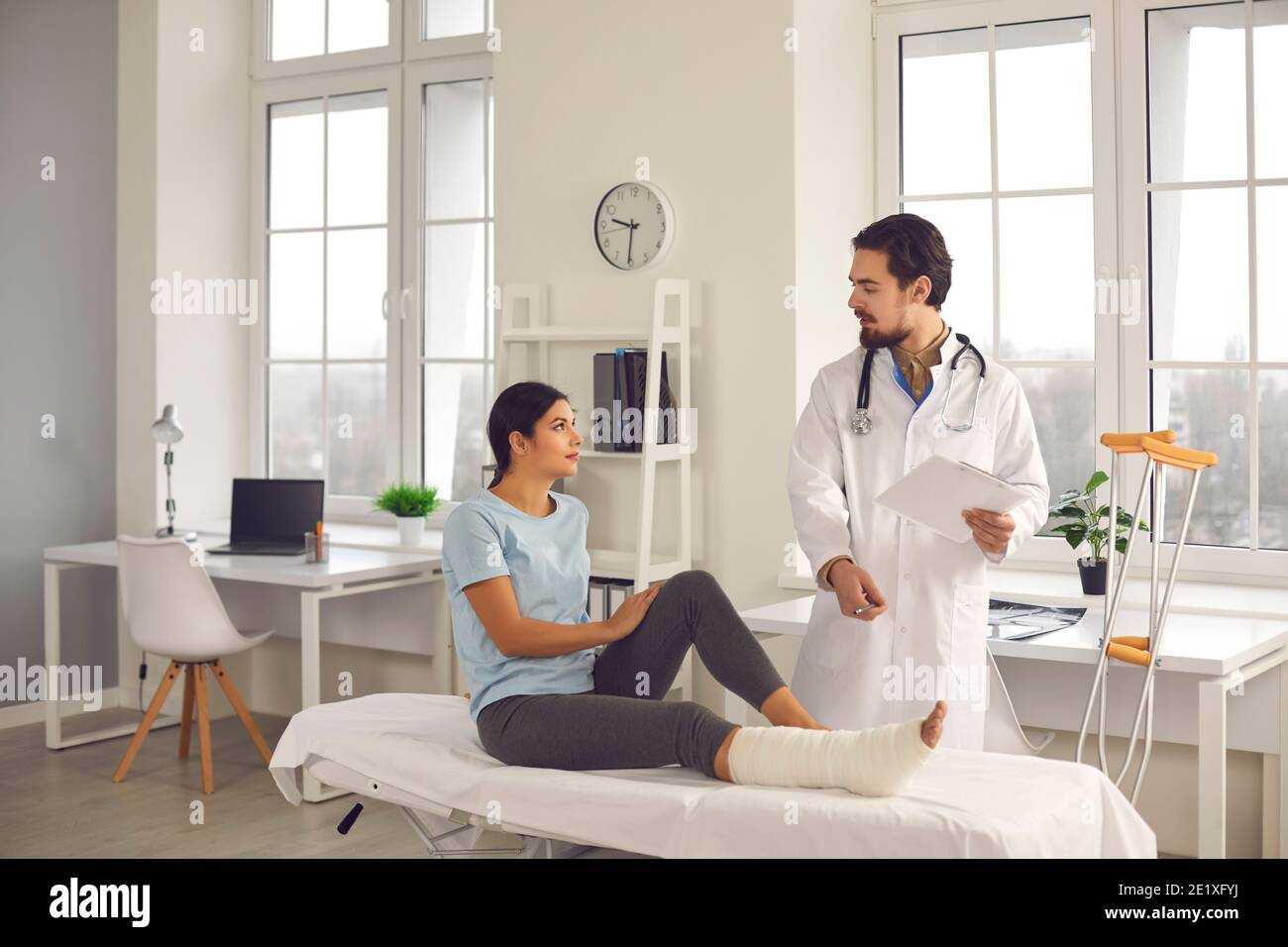 Orthopedic surgeon interviewing woman with broken leg and giving her recovery advice Stock Photo