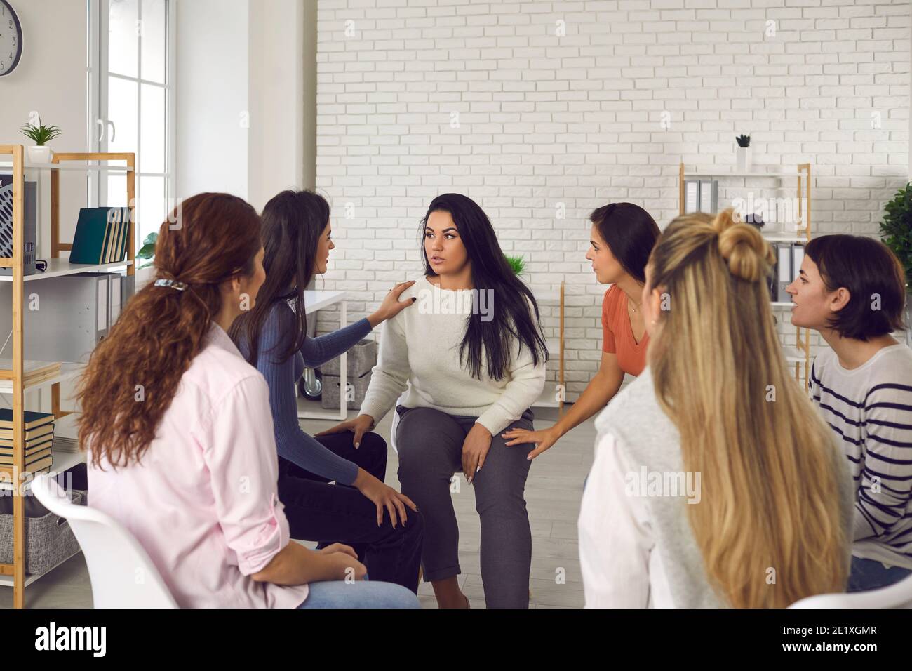 Young women sharing their life stories in therapy session or support group meeting Stock Photo