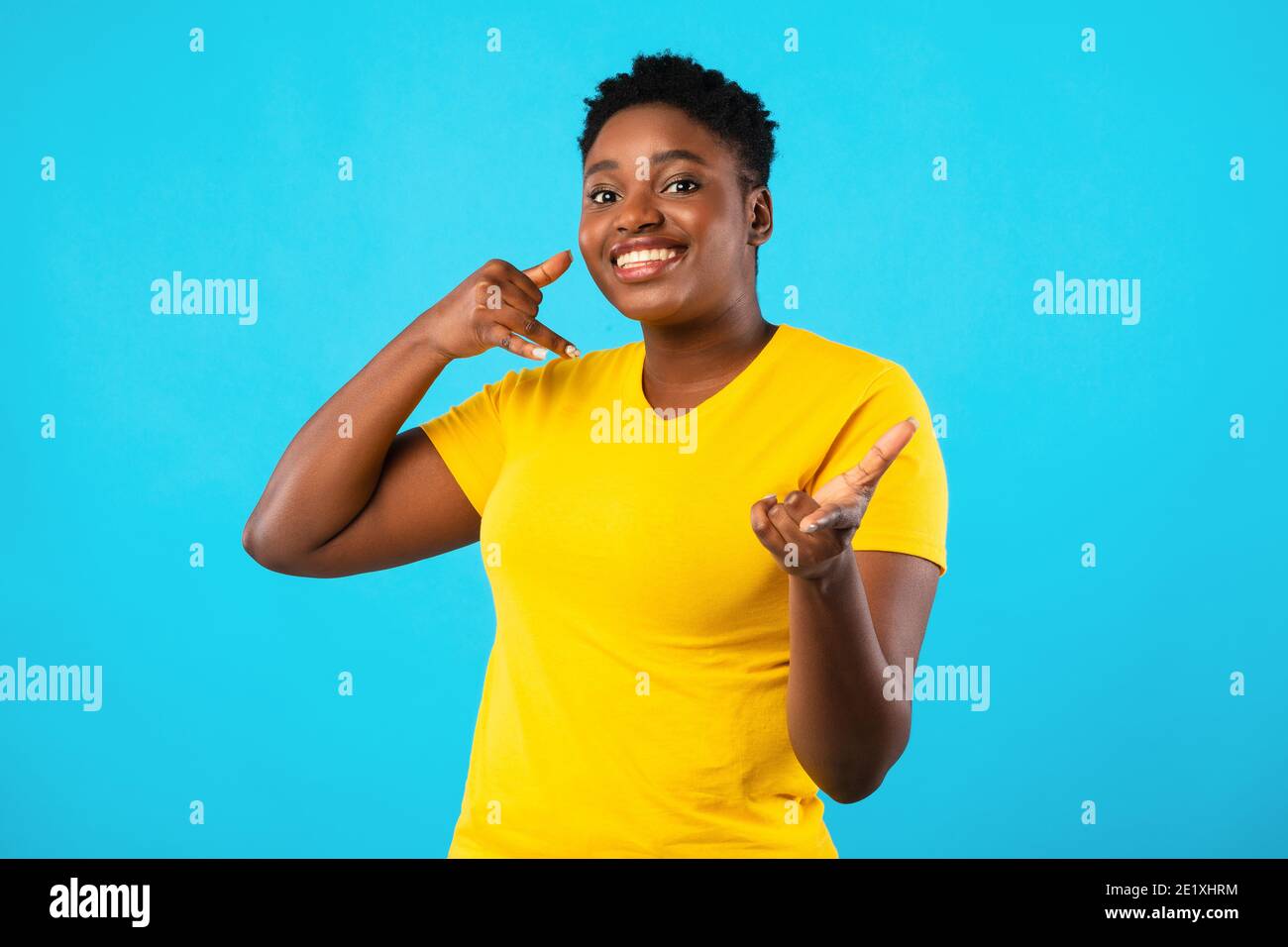 Plus-Size African Woman Gesturing Call Me Over Blue Background Stock Photo