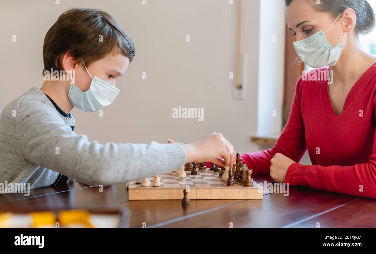 Mother and kid during coronavirus crisis playing chess at home Stock Photo