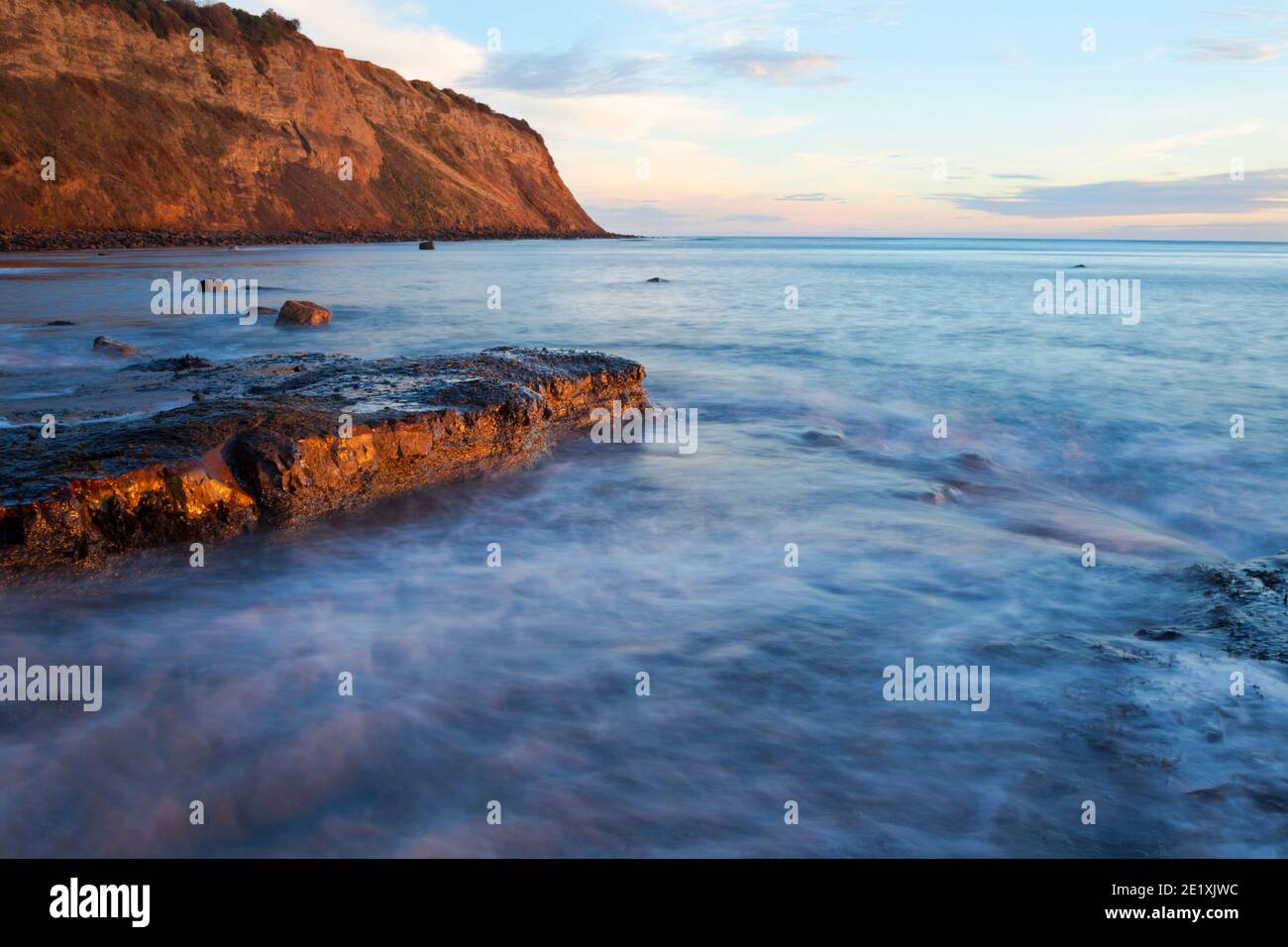 Fast moving incoming tide at Robin Hood's Bay just after sunrise looking towards North Cheeck (also known as Ness Point) Stock Photo