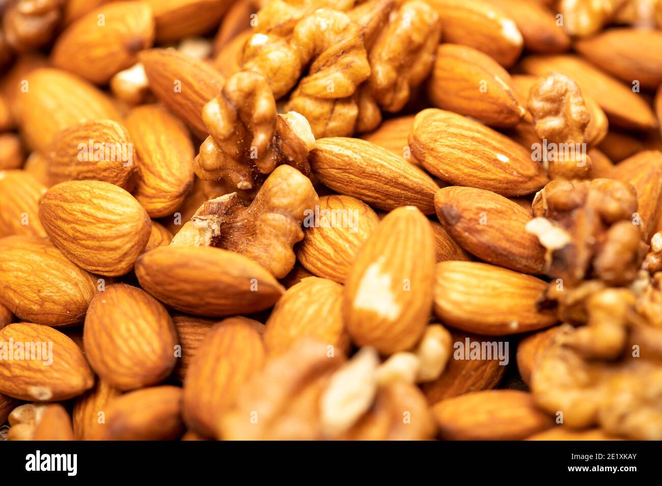 Almonds and walnuts scattered on the table. Close-up, selective focus Stock Photo