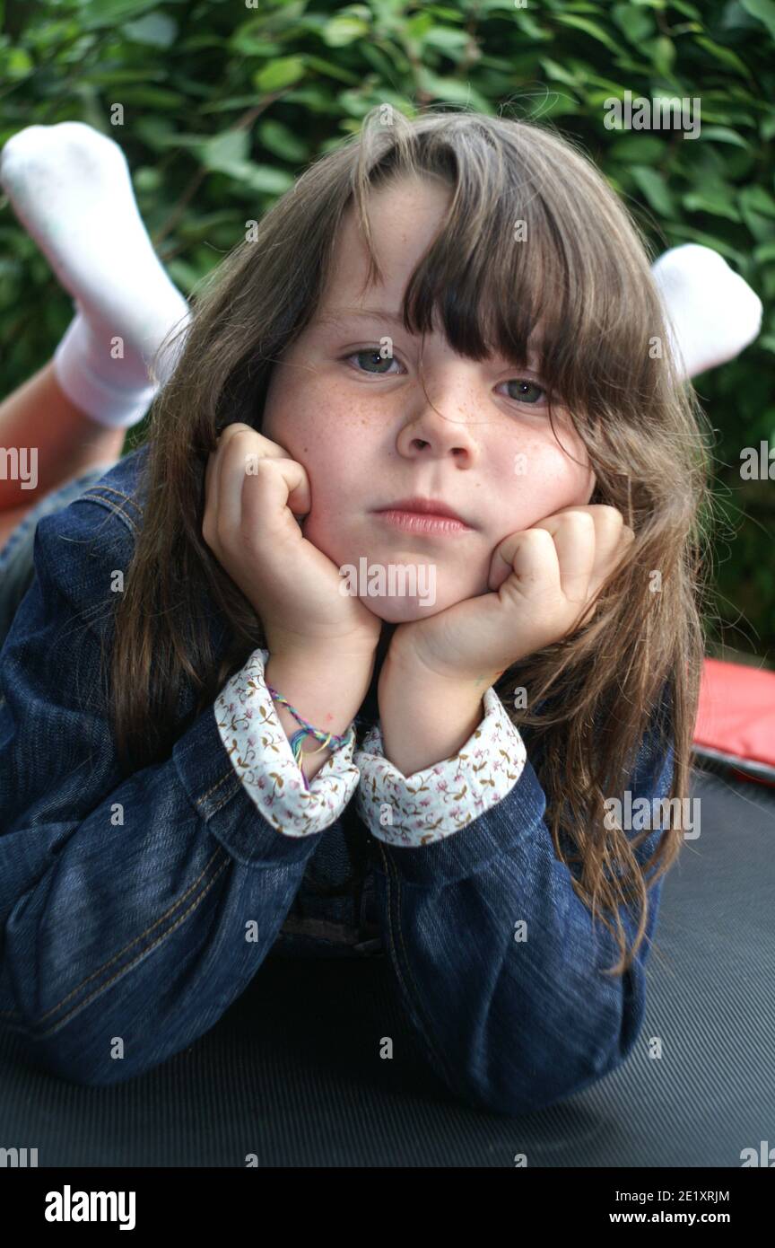 Young girl dressed in a blue denim jacket lying on a trampoline