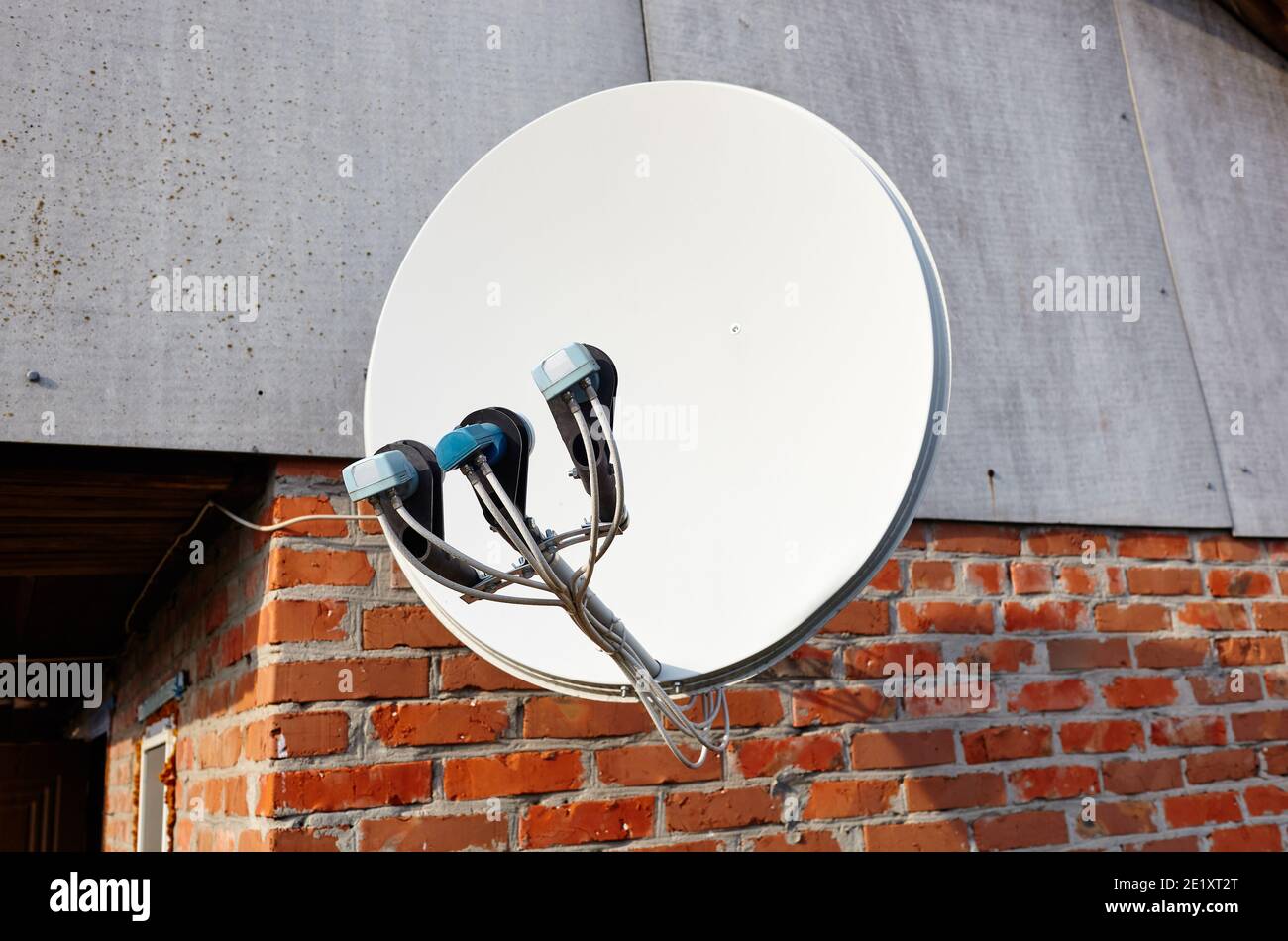 Satellite dish is attached to the wall of the house. A domestic