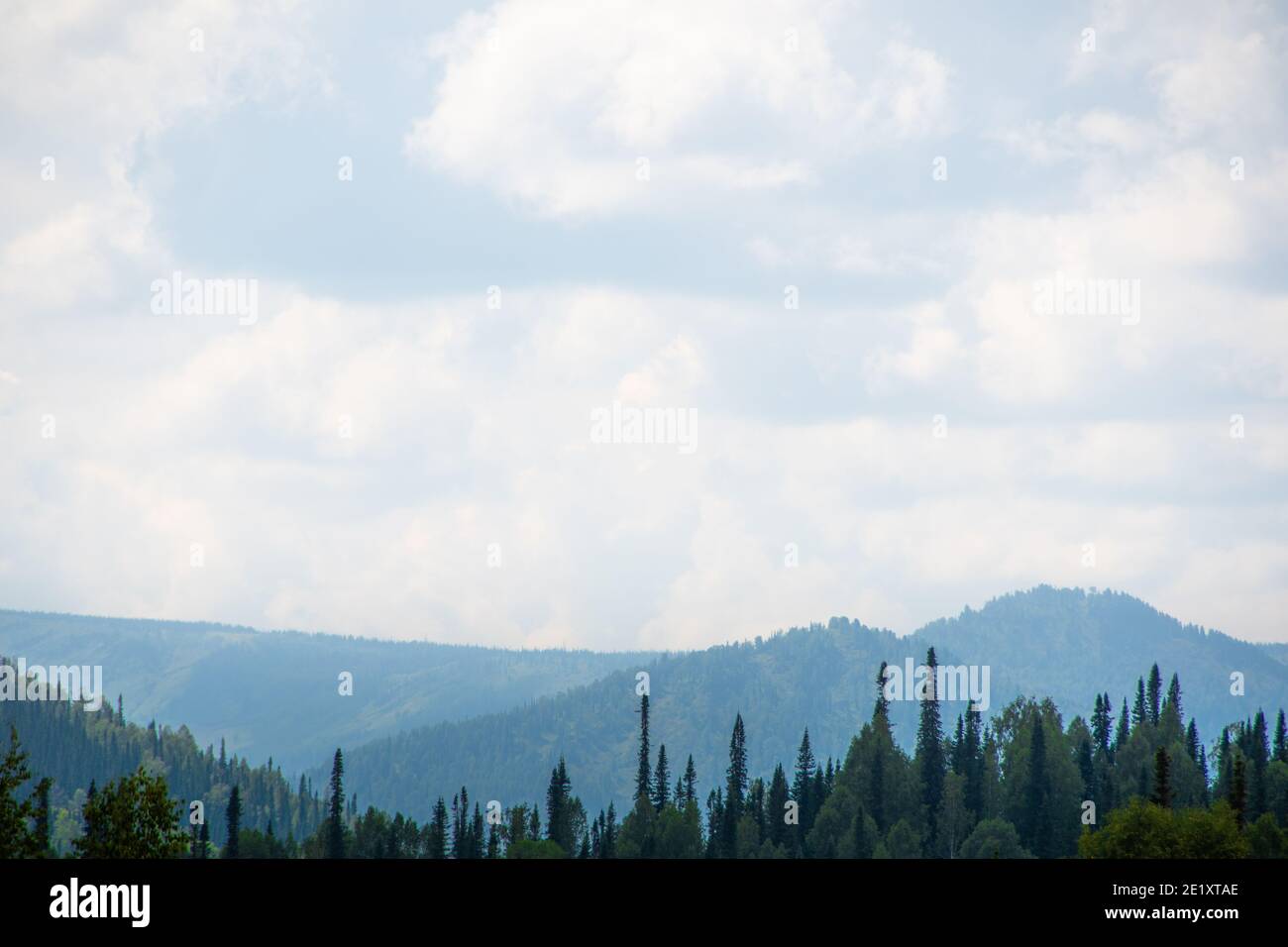 Rocky ridge on horizon under blue cloudy sky. Mountain valley for travel. Adventure travel, tourism and conservation concept. Stock Photo