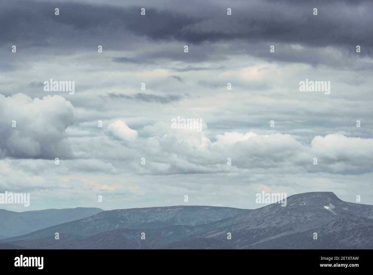 Thick clouds over mountain range, hills in blue haze Stock Photo