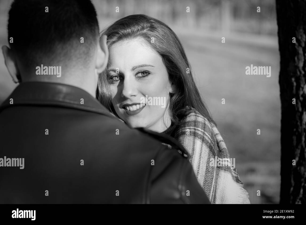Young woman stands next to boyfriend with smile while looking to the side. Black and white photography. Valentine Day, dating concepts Stock Photo