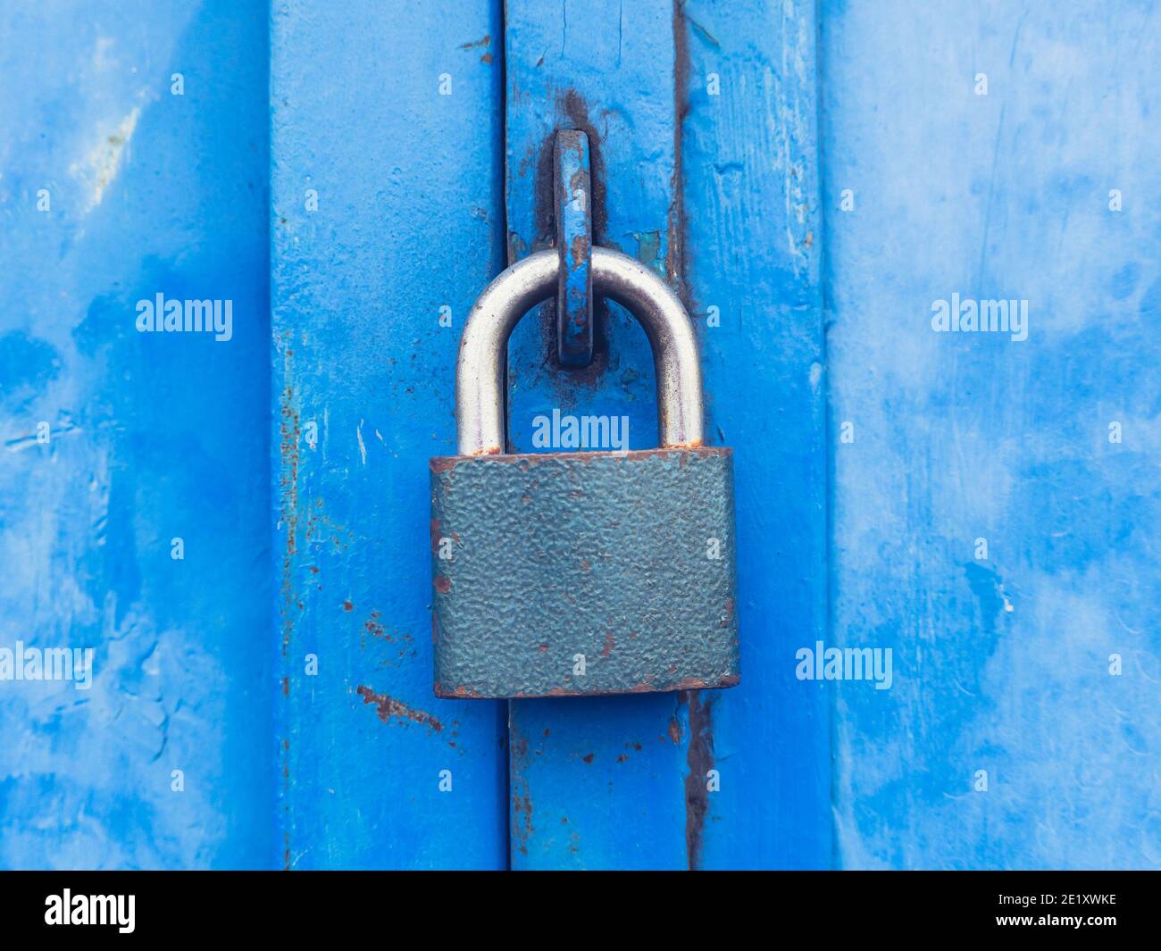 Hardened padlock hang in eye bolt on blue industrial metal door