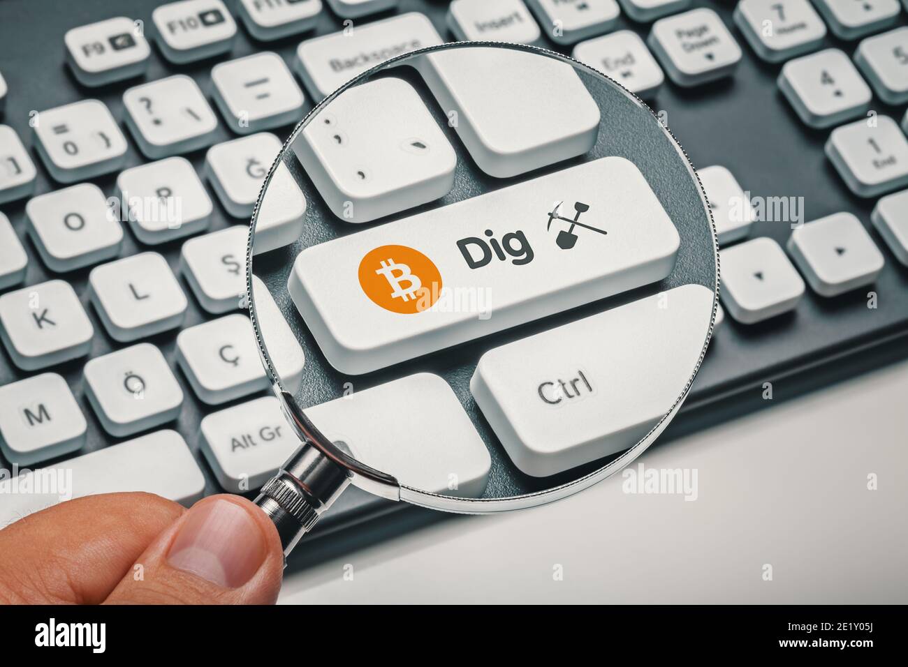 magnifying glass in hand focused on computer key with bitcoin symbol and dig word with symbol Stock Photo