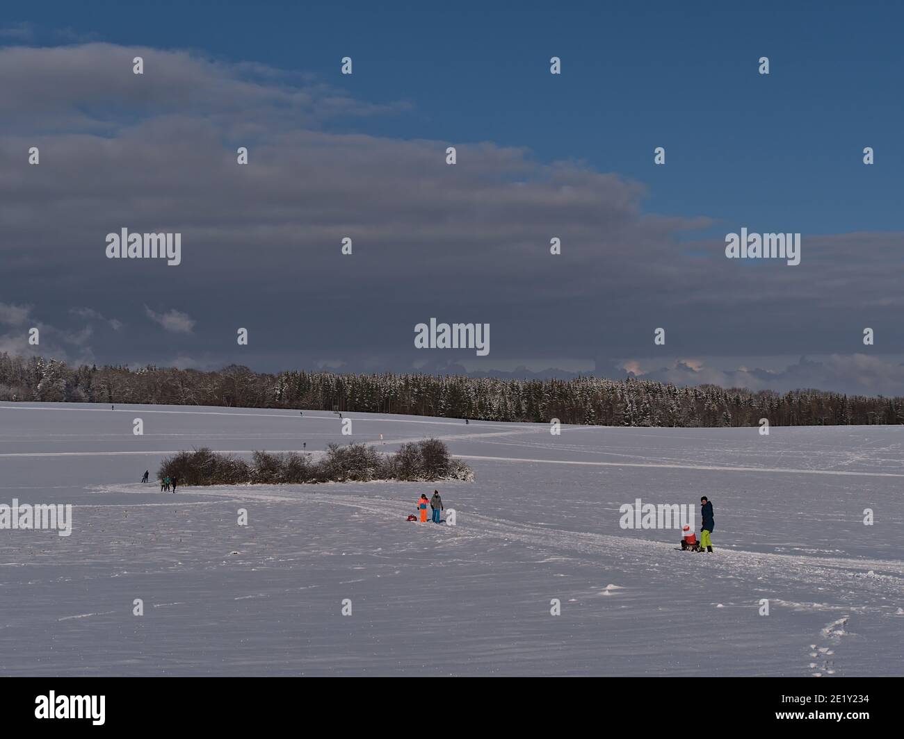 Burladingen, Germany - 01-09-2021: Beautiful winter landscape with snow-covered fields and people enjoying winter sport activities. Stock Photo