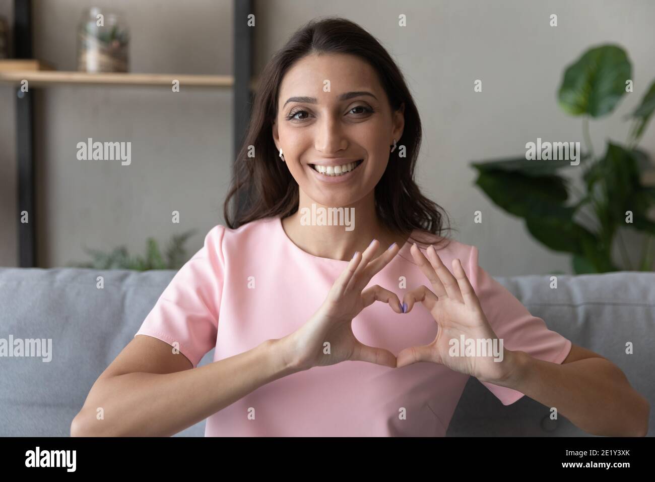 Portrait of happy ethnic woman show love gesture Stock Photo