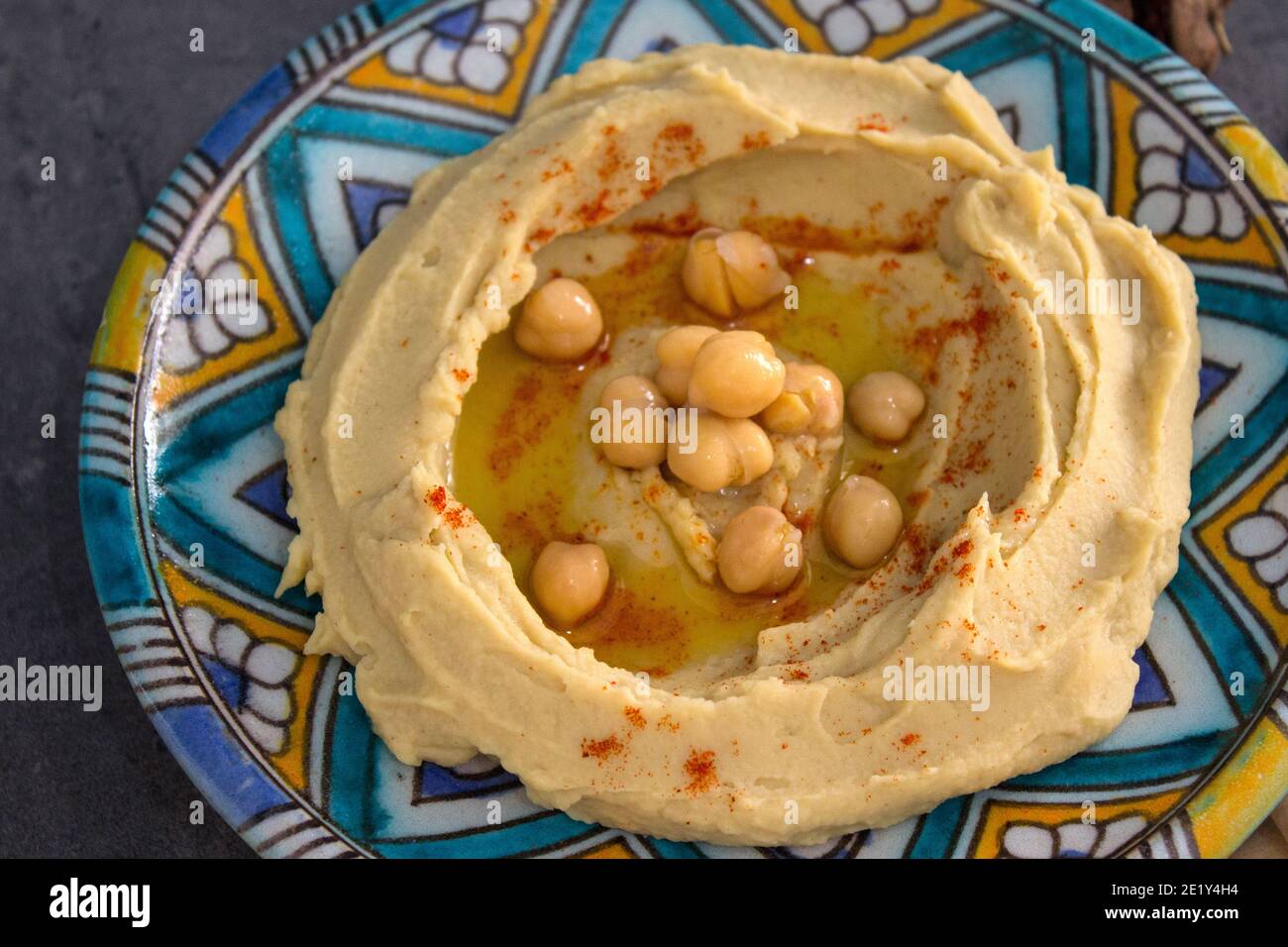 Tasty hummus on colorful plate. Top view photo of traditional food of Israel. Balanced diet concept.  Classic israeli hummus. Stock Photo