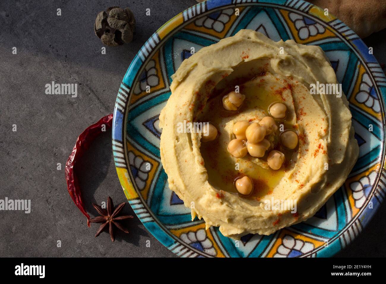 Close up photo of fresh homemade hummus on colorful ceramic plate. Balanced meal photo. Healthy eating concept. Authentic food of Middle East. Stock Photo