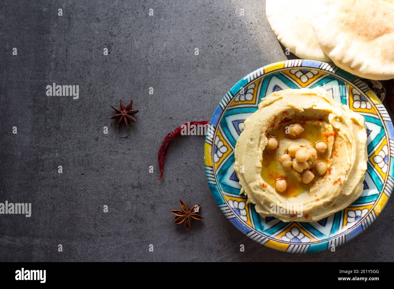 Close up photo of fresh homemade hummus on colorful ceramic plate. Balanced meal photo. Healthy eating concept. Authentic food of Middle East. Stock Photo