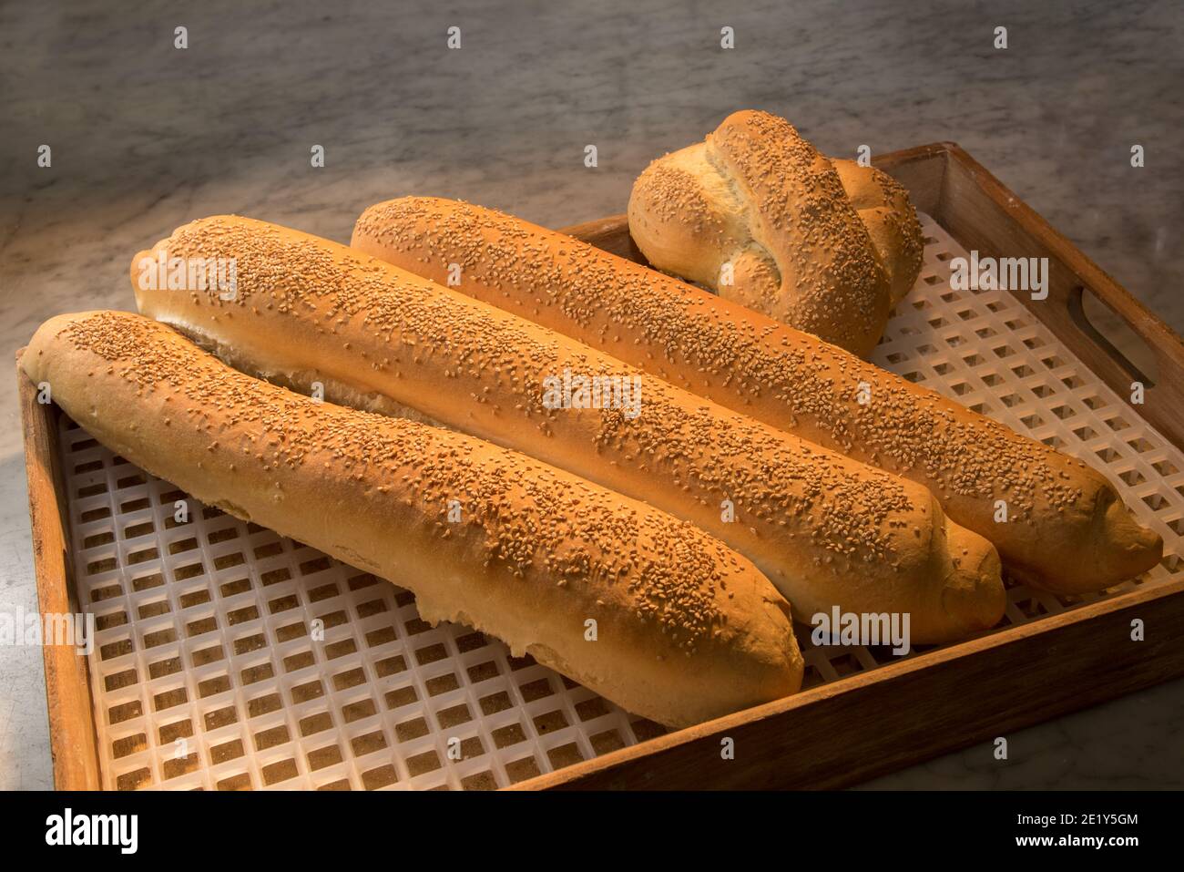 Freshly baked loaves with sesame seeds. Baguette bread in wooden tray Stock Photo