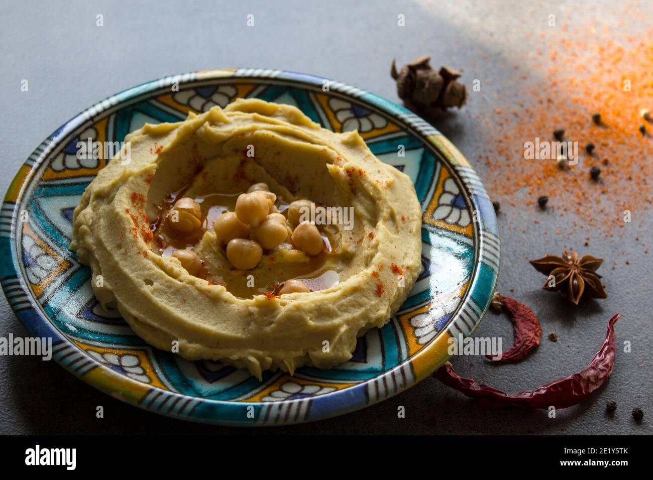 Close up photo of fresh homemade hummus on colorful ceramic plate. Balanced meal photo. Healthy eating concept. Authentic food of Middle East. Stock Photo