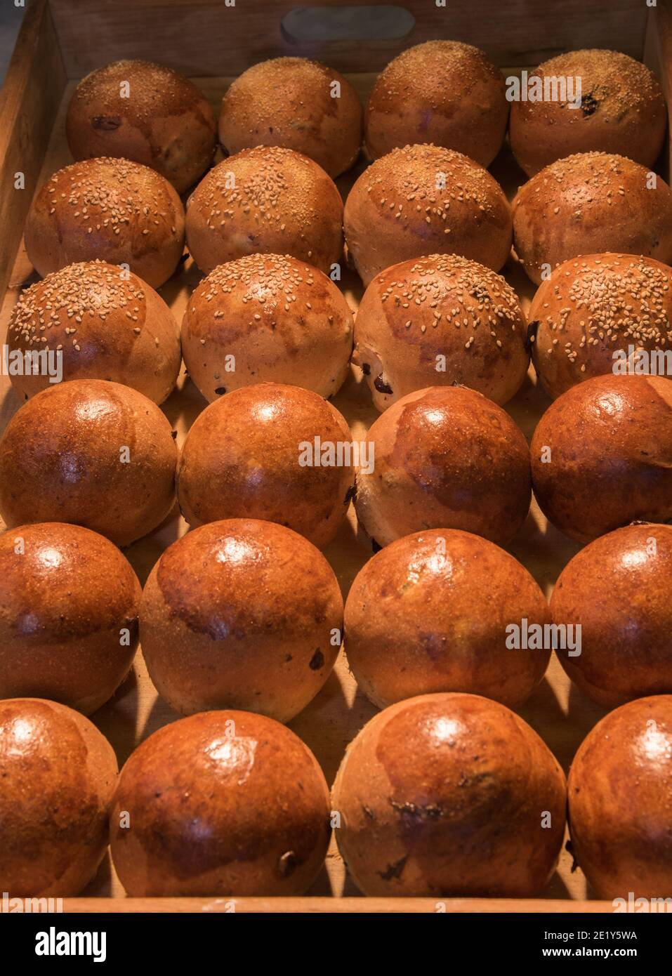 dinner roll pan - many small loaves with and without sesame seeds in wooden tray Stock Photo
