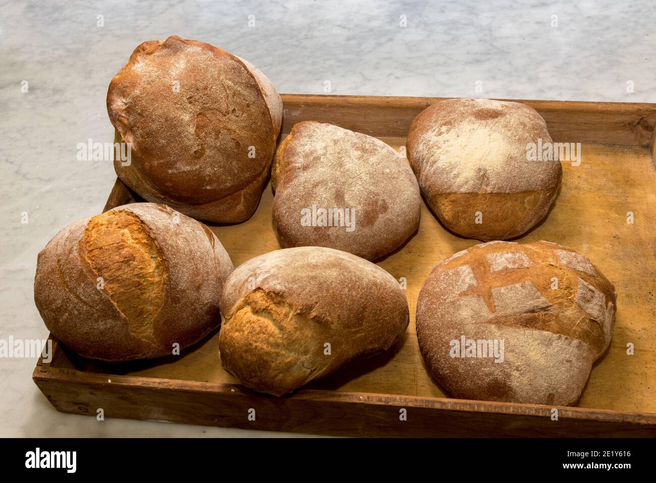 rustic country bread, six well-cooked loaves in a wooden tray Stock Photo