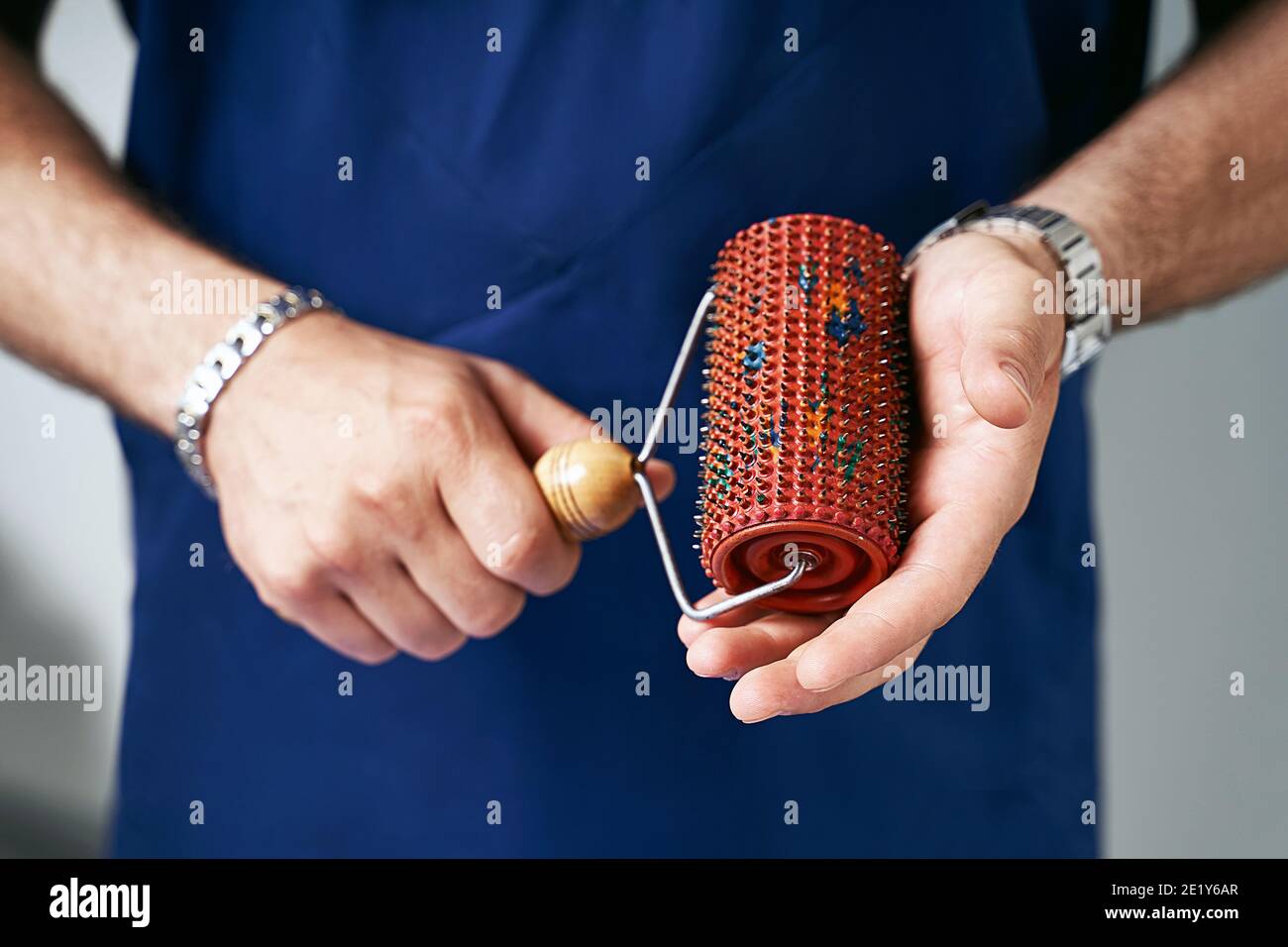 Male massage therapist doctor or masseur hands holding a hedgehog barbed massage roller Stock Male massage therapist doctor or masseur hands holding a hedgehog barbed massage roller Stock