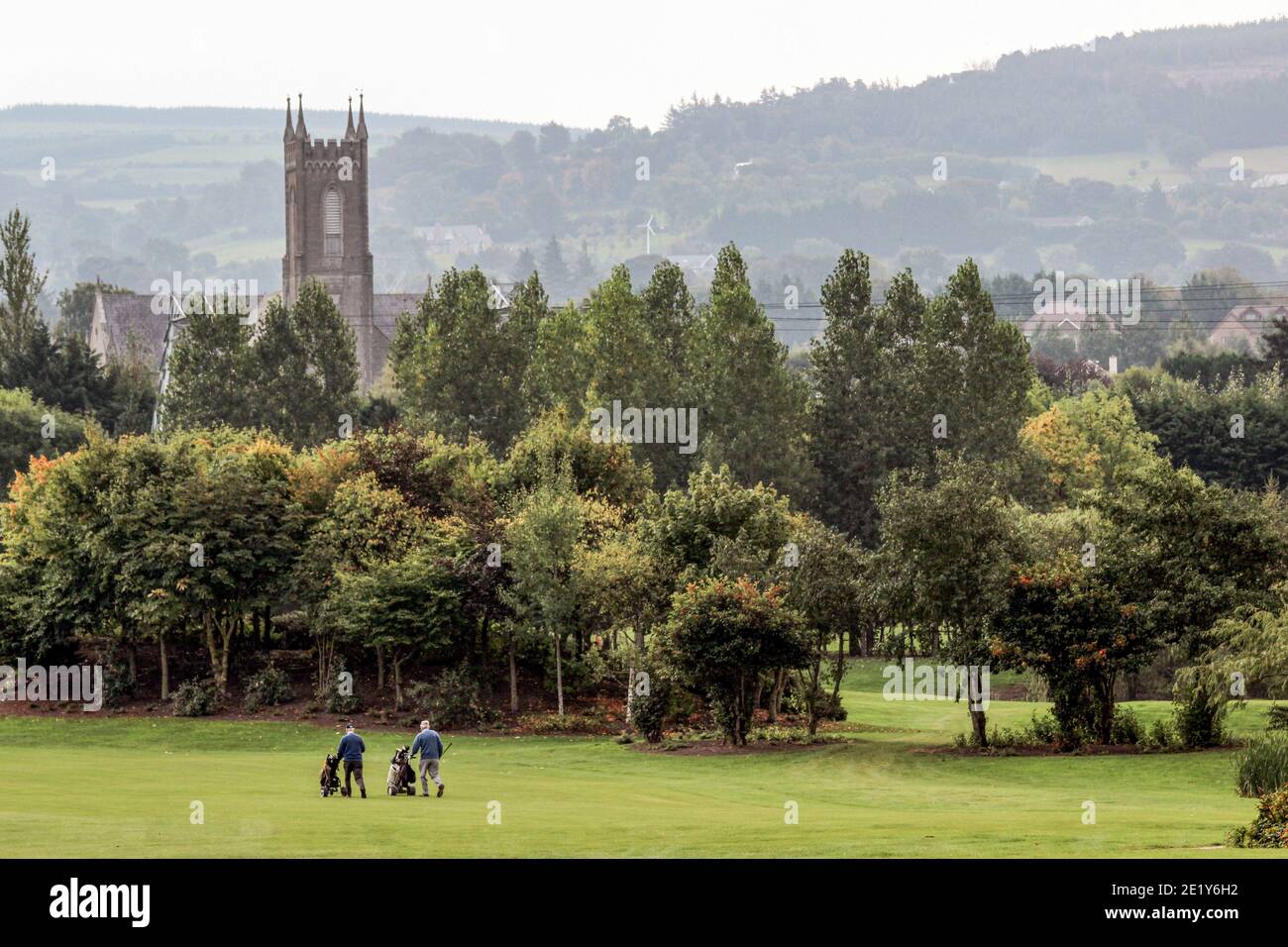 Two golfers on golf course with Roman Catholic Church in the background in Dublin, Ireland Stock Photo