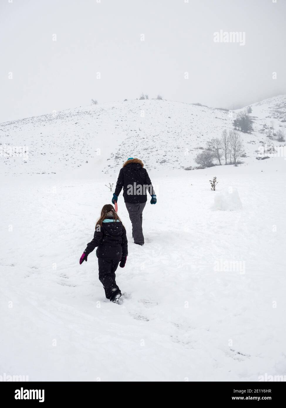 Two people walking through the snow Stock Photo - Alamy