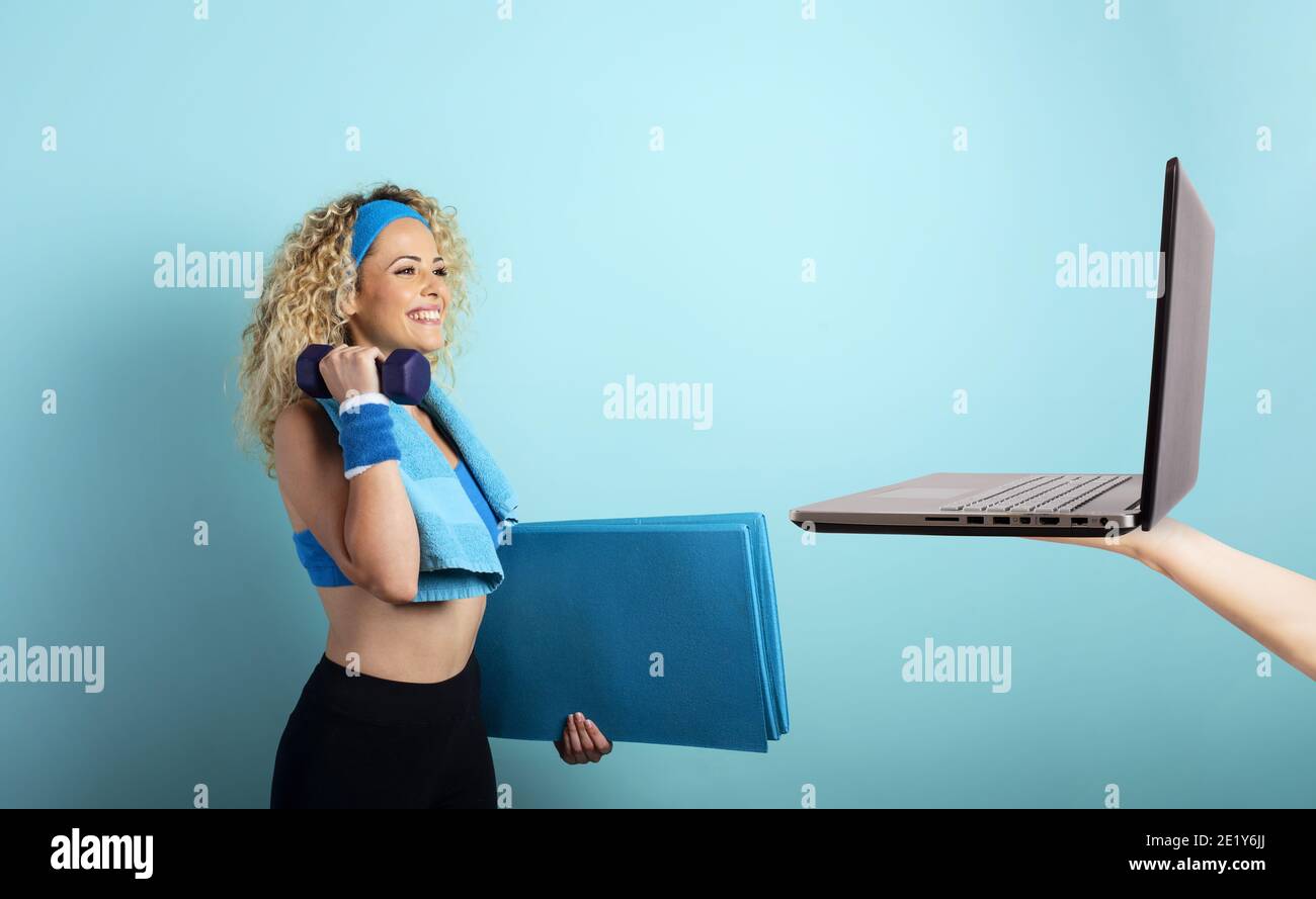 Girl with handlebars ready to start the gym online with a computer. cyan background Stock Photo
