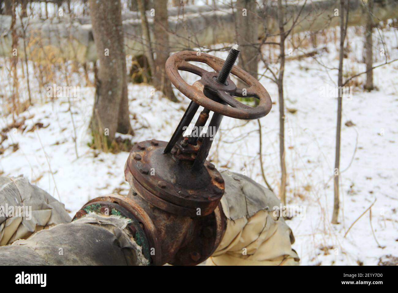 Old damaged and rusty iron oil pipe valve wheel. Metal, pipeline and mechanic concept. An old iron valve on a gas pipe. A valve to cover the pipe with a round handle. Stock Photo