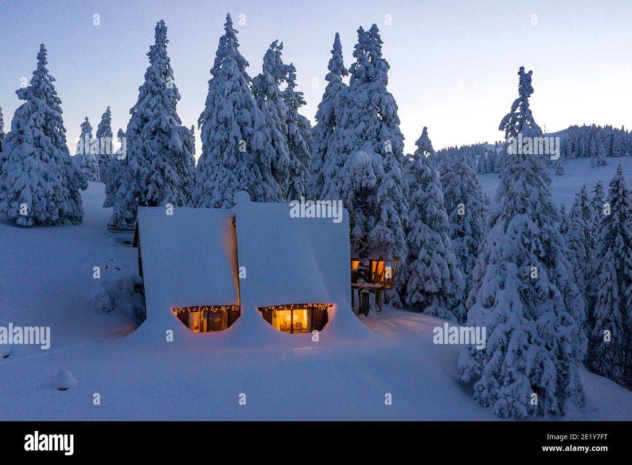 Fantastic winter landscape with wooden house with light in windows in ...