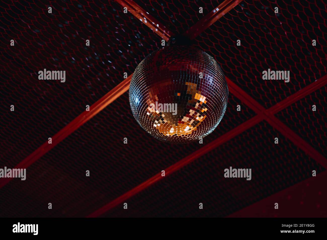 mirrored disco ball attached to the red ceiling. disco party entertainment Stock Photo