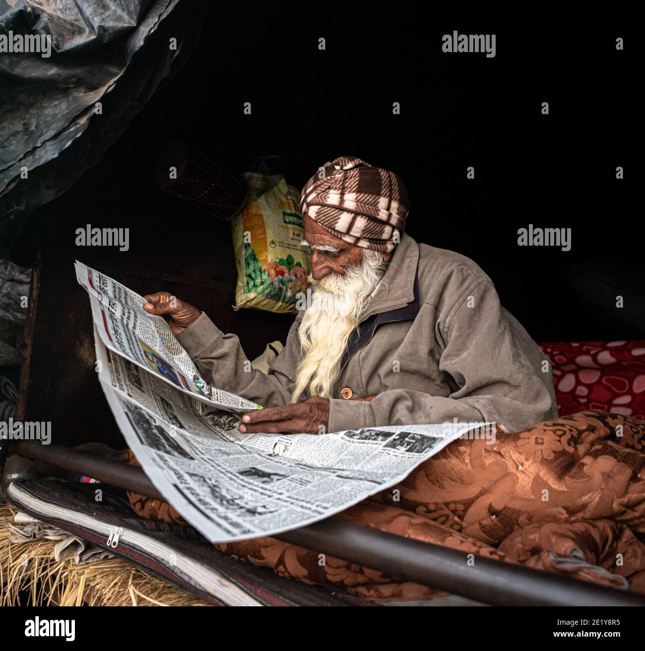 A PORTRAIT OF A FARMER PROTESTER READING NEWS PAPER AT DELHI BORDER , THEY ARE PROTESTING AGAINST NEW FARM LAW PASSED BY INDIAN GOVERNMENT. Stock Photo