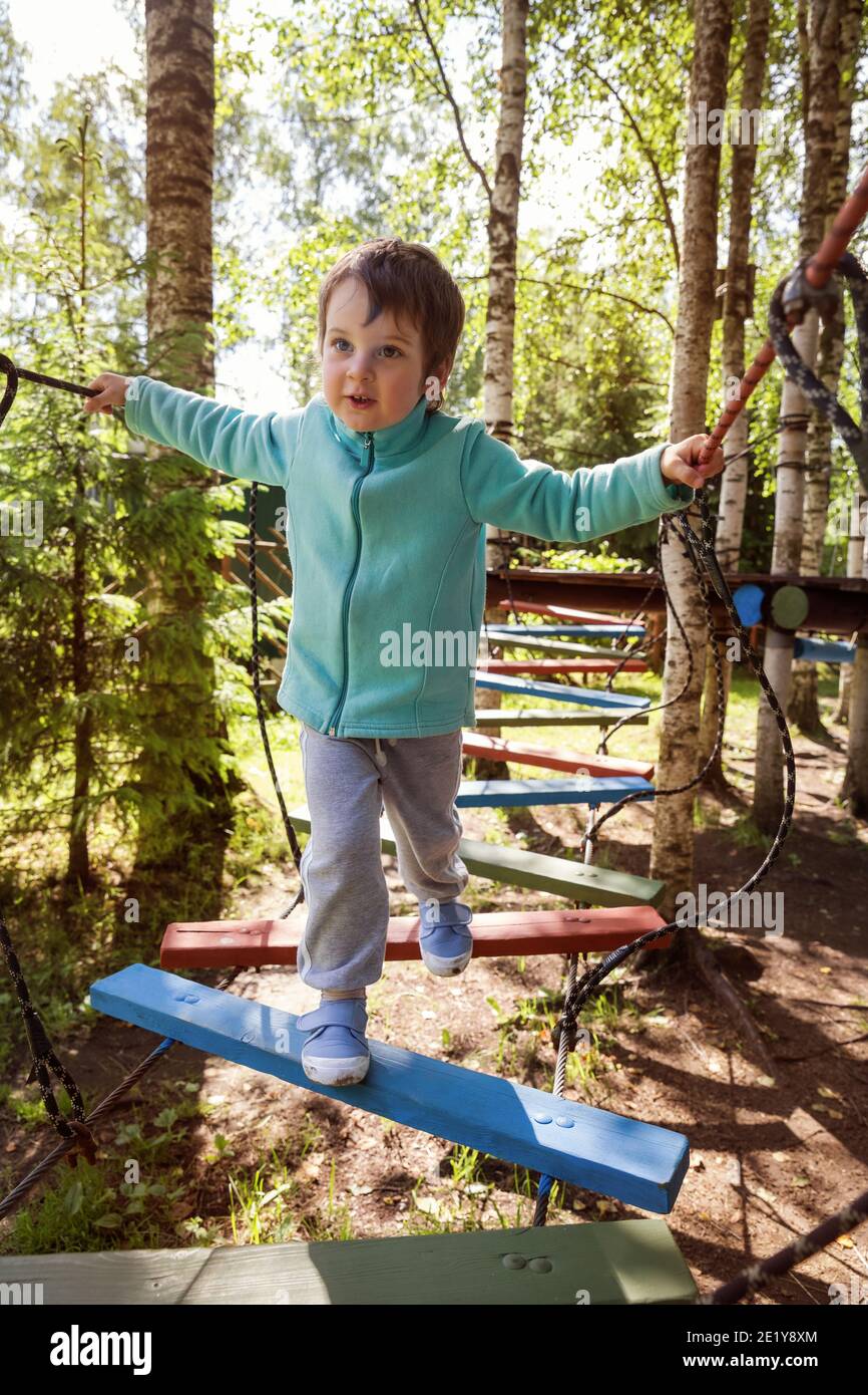 Children's obstacle course. Preschooler boy bravely walks the rope