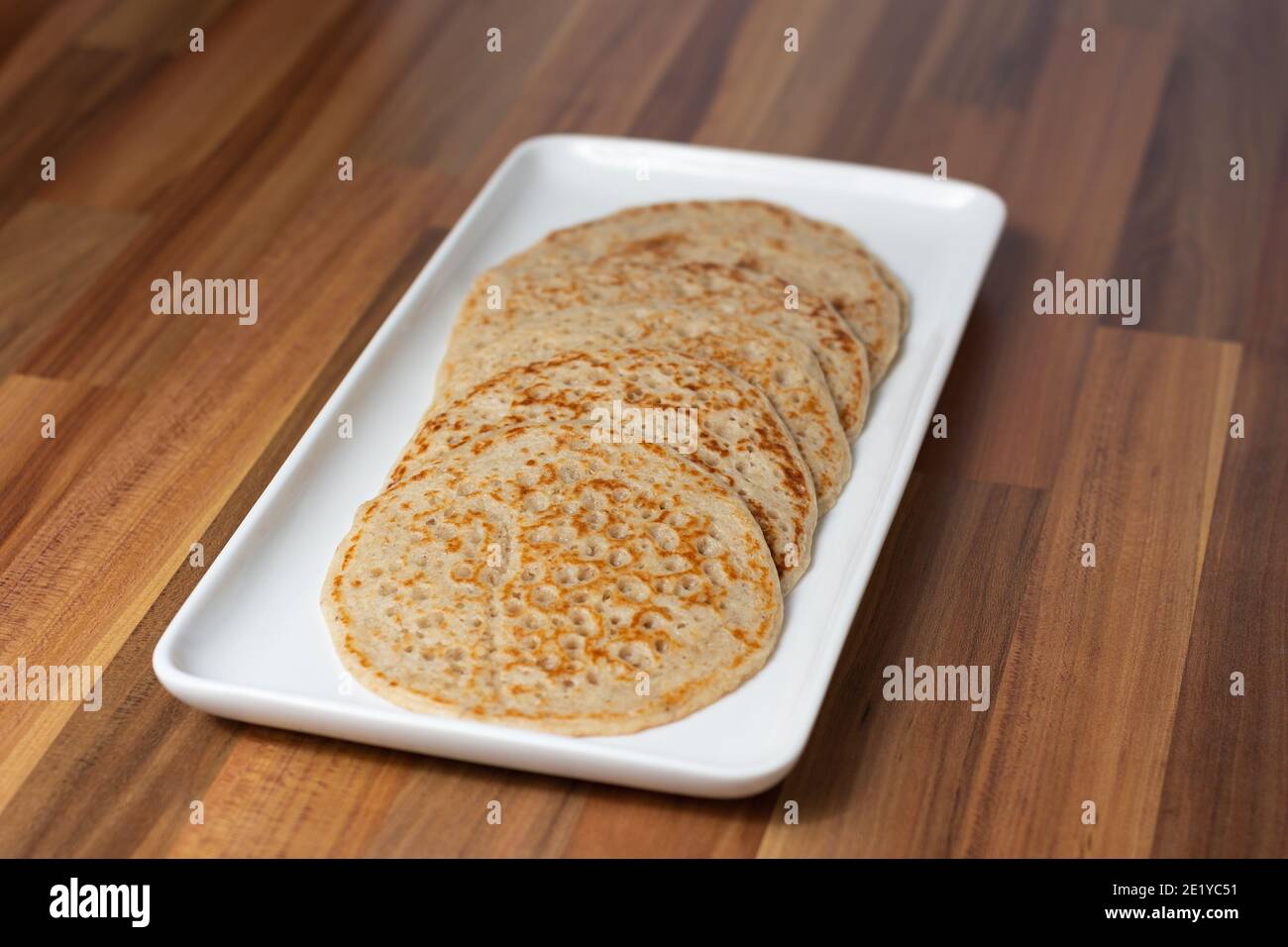 Derbyshire oatcakes on a white platter viewed from an angle with a wooden backdrop Stock Photo
