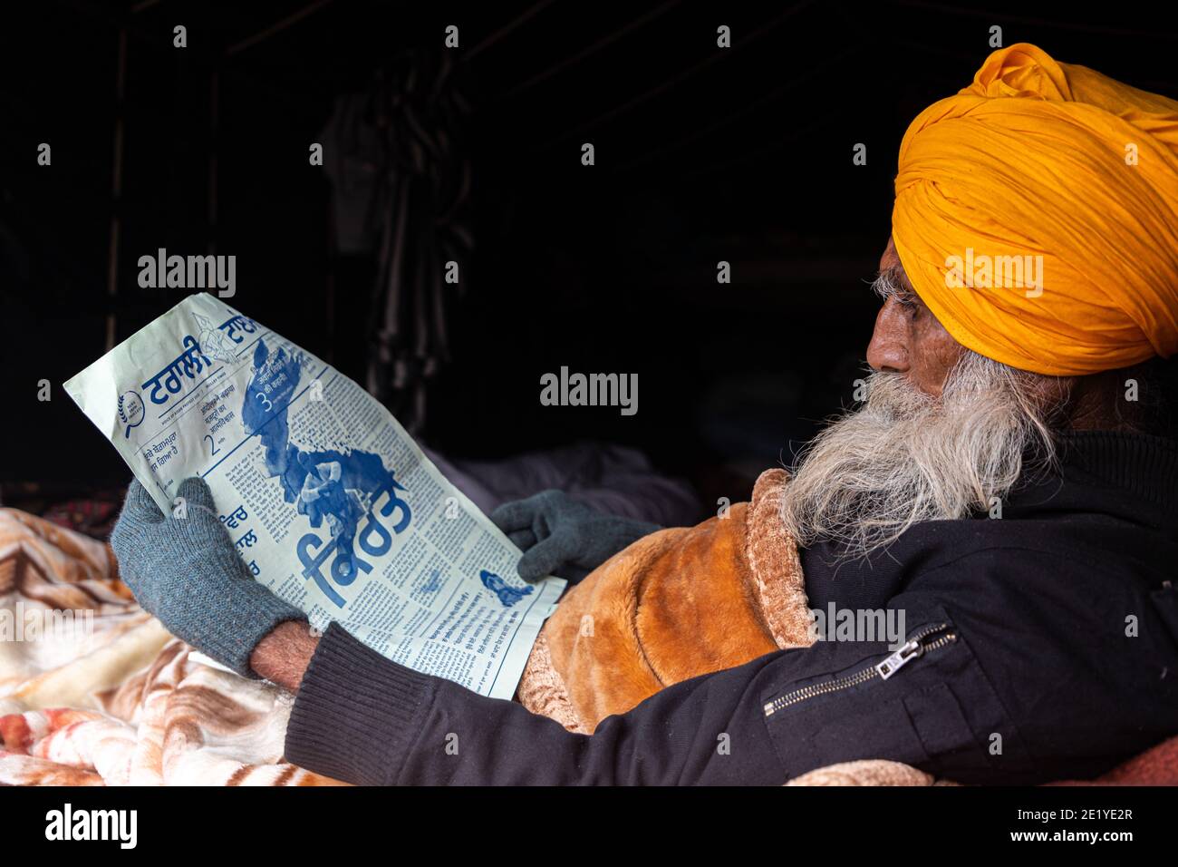 A PORTRAIT OF A FARMER PROTESTER READING NEWS PAPER AT DELHI BORDER , THEY ARE PROTESTING AGAINST NEW FARM LAW PASSED BY INDIAN GOVERNMENT. Stock Photo